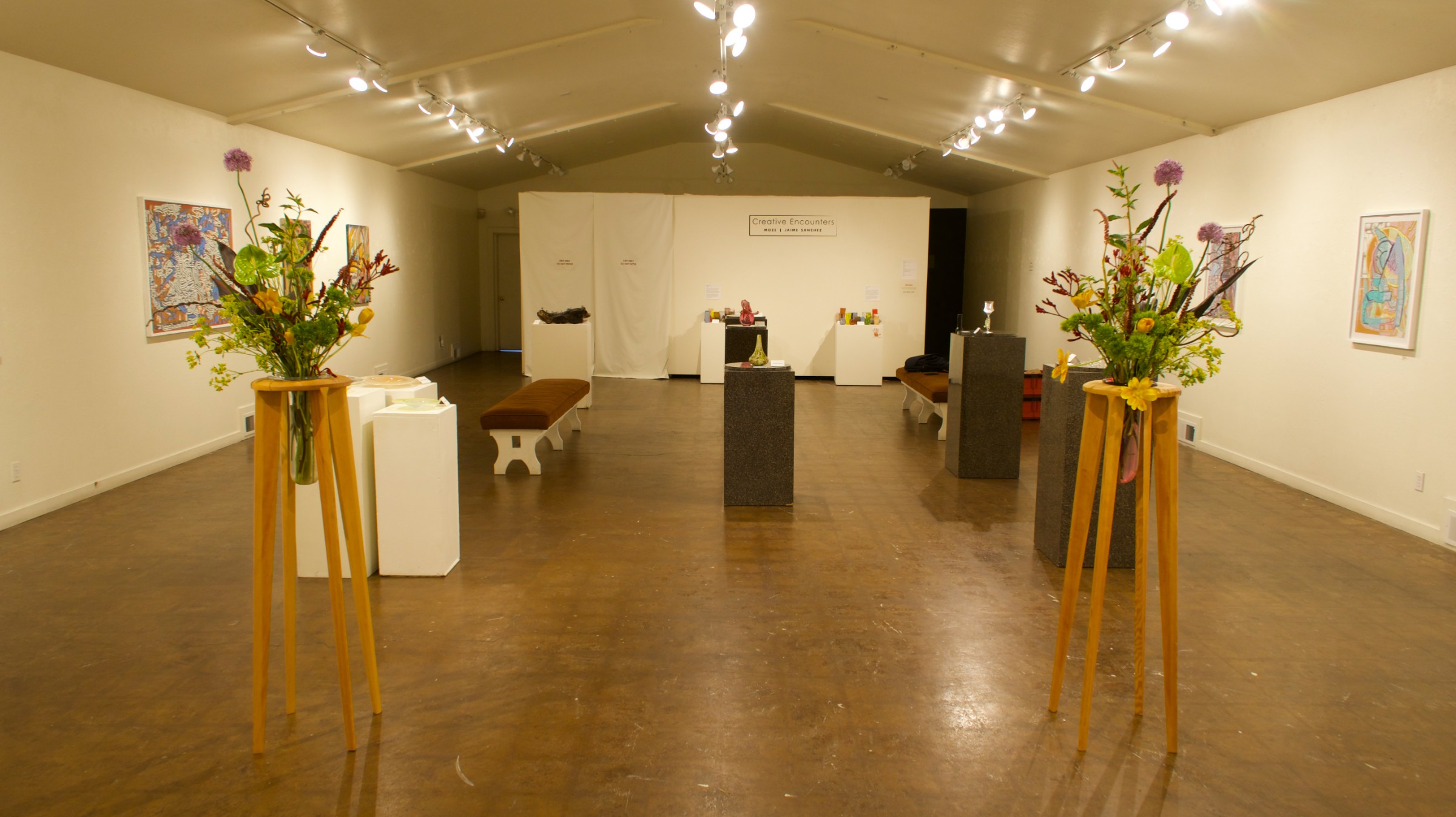 Creative Encounters installation view at the Santa Cruz Art League — glass works on pedestals with paintings on the walls